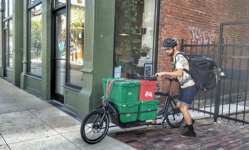 Person loading a cargo bike with containers.