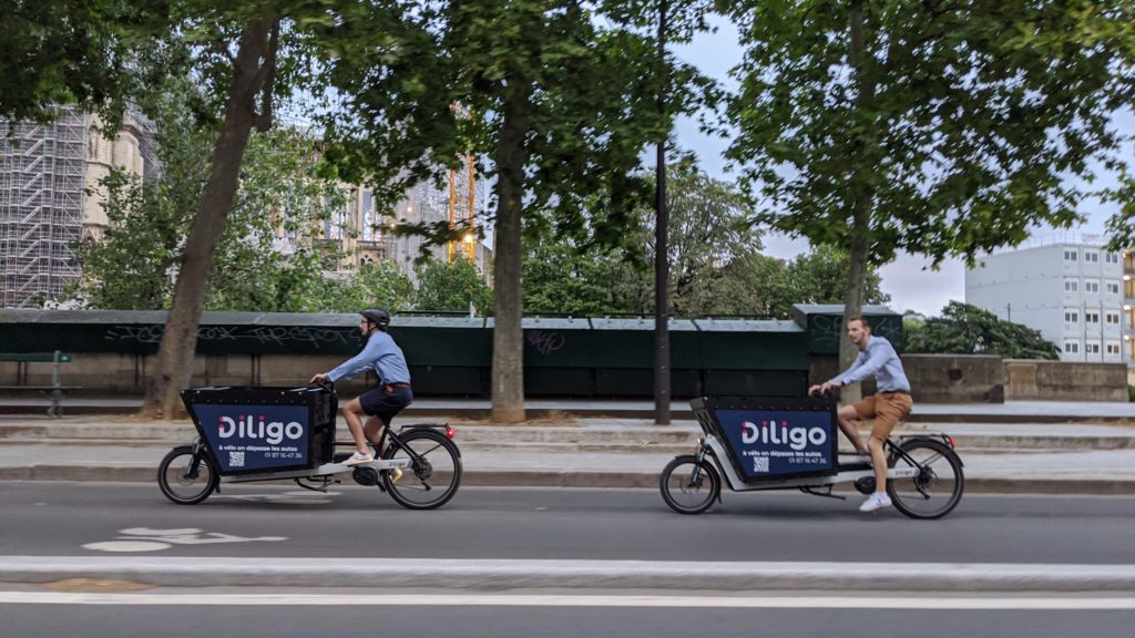Two bike riders ride their bikes in a bike lane in Paris.