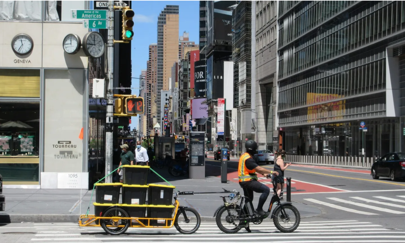 A bike delivery driver transports containers on a city street.
